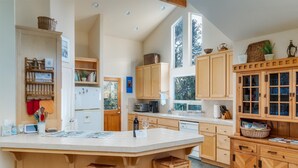 Une cuisine spacieuse dotée d’un grand îlot central, de meubles en bois et offrant une vue sur l’extérieur.