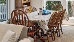 Comedor con mesa dispuesta para seis personas, sillas de madera, una araña y un aparador de madera con puertas de cristal.