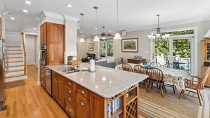 Una cocina amplia con armarios de madera, encimera de granito y comedor con mesa y sillas.