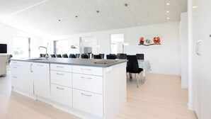 Une cuisine moderne avec des meubles blancs, un îlot central et un coin repas avec des chaises noires.