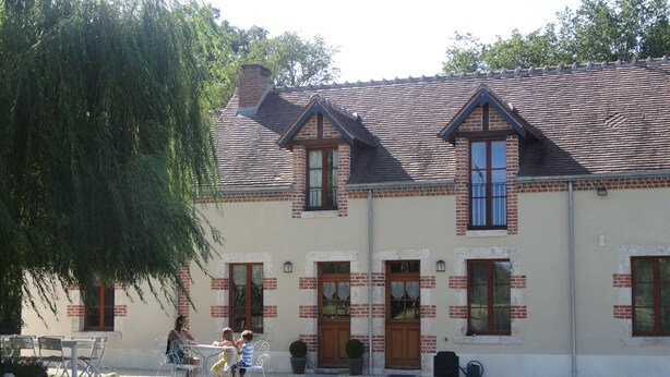 A two-story house with a tiled roof, brick exterior, and multiple windows.