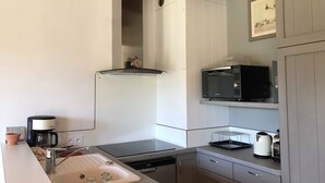 A modern kitchen with a built-in microwave, coffee maker, and dishwasher. - Ty Bihan Small stone house in a quiet location 5 minutes from the beach (FOUESNANT)