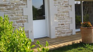 A stone building with a wooden deck and a potted plant. - Ty Bihan Small stone house in a quiet location 5 minutes from the beach (FOUESNANT)