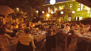 Een terras met ronde tafels en aanwezige gasten.