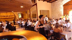 Een restaurant met houten balken en stenen muren, tafels gedekt voor diners, en een bar.