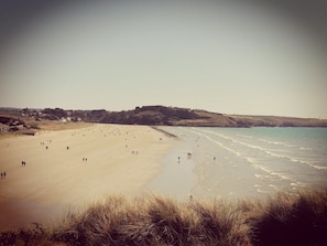 A beach with people walking along the shore and a few buildings in the background. - Maison à 200 mètres de la plage (Plomodiern)