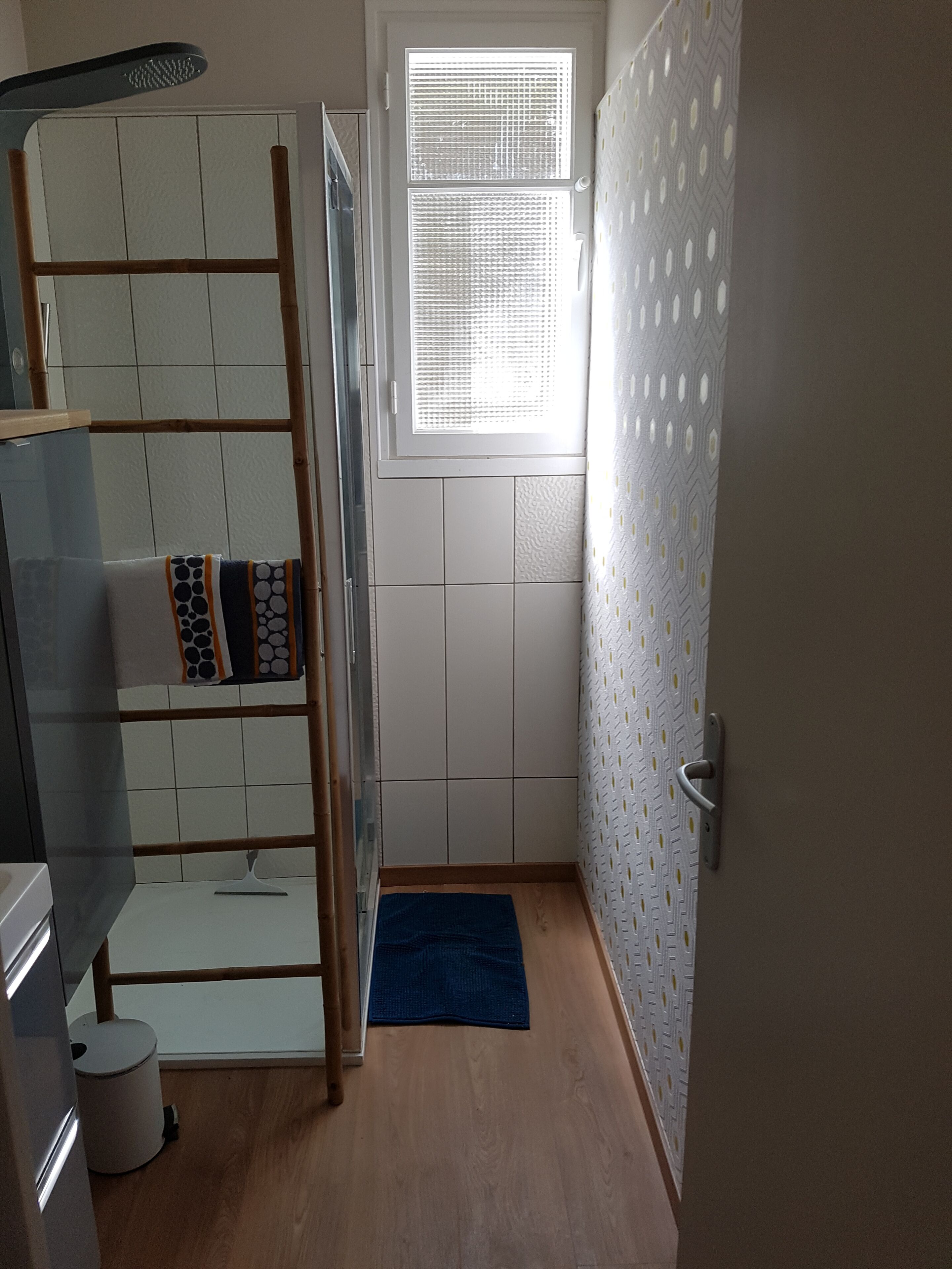 A bathroom with a shower, a toilet, a sink, a window, and a towel rack.