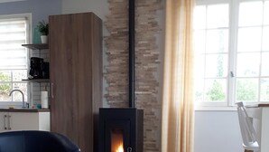Ett modernt vardagsrum med en vedkamin, en blå soffa och ett matbord med en dekorativ lampa.