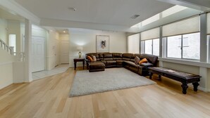 A spacious living room with a large sectional sofa, a coffee table, and a rug. There is a staircase leading to another level, and a window providing natural light. - Why Stay in the confinement of a hotel, when Ucan stay in this Las Vegas Oasis. (Las Vegas)