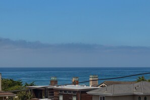 A coastal view with a clear sky, a body of water, and residential buildings with visible chimneys and rooftops. - Sea'Scape : 2  BR, 2  BA House in Cambria, Sleeps 4 (Cambria)