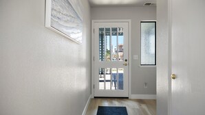 A hallway with a white door, a blue rug, and a painting on the wall. - Sea'Scape : 2  BR, 2  BA House in Cambria, Sleeps 4 (Cambria)