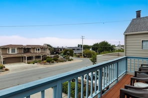 A residential street with houses, a clear sky, and a wooden deck with chairs. - Sea'Scape : 2  BR, 2  BA House in Cambria, Sleeps 4 (Cambria)