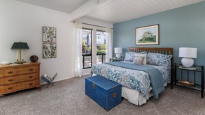 A bedroom with a bed, nightstands, a dresser, and a window.