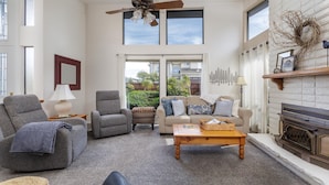 A living room with a fireplace, two sofas, a coffee table, and a ceiling fan.