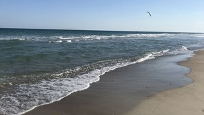A beach with waves, a clear sky, and a kite flying. - Great Ocean View! Quiet Cul-de-sac, 4 minute walk to Beach, Waterpark, Shopping  (Emerald Isle)