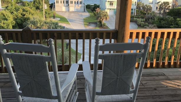 A wooden deck with two wicker chairs facing a view of a residential area with houses and a road. - Great Ocean View! Quiet Cul-de-sac, 4 minute walk to Beach, Waterpark, Shopping  (Emerald Isle)