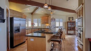 A spacious kitchen with a large island, wooden cabinets, and a stainless steel refrigerator. - Bristol By the Sea: 3  BR, 3  BA House in Cambria, Sleeps 8 (Cambria)