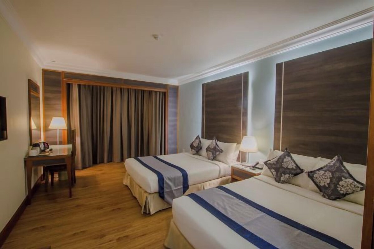 Une chambre d’hôtel avec deux lits, un bureau et une chaise.