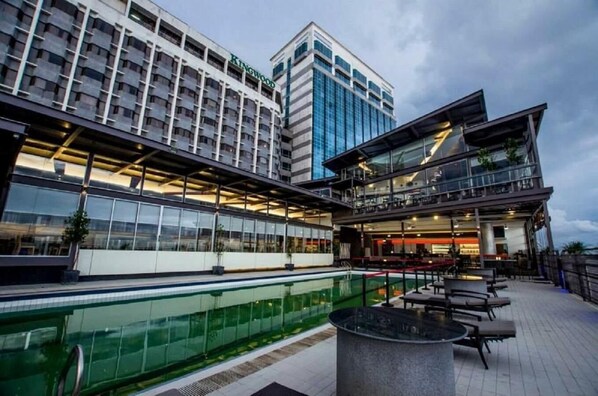 Un hotel con piscina, mobiliario exterior y un diseño arquitectónico moderno.