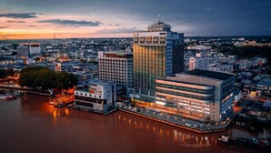 Un paisaje urbano con edificios modernos, un río y un atardecer.