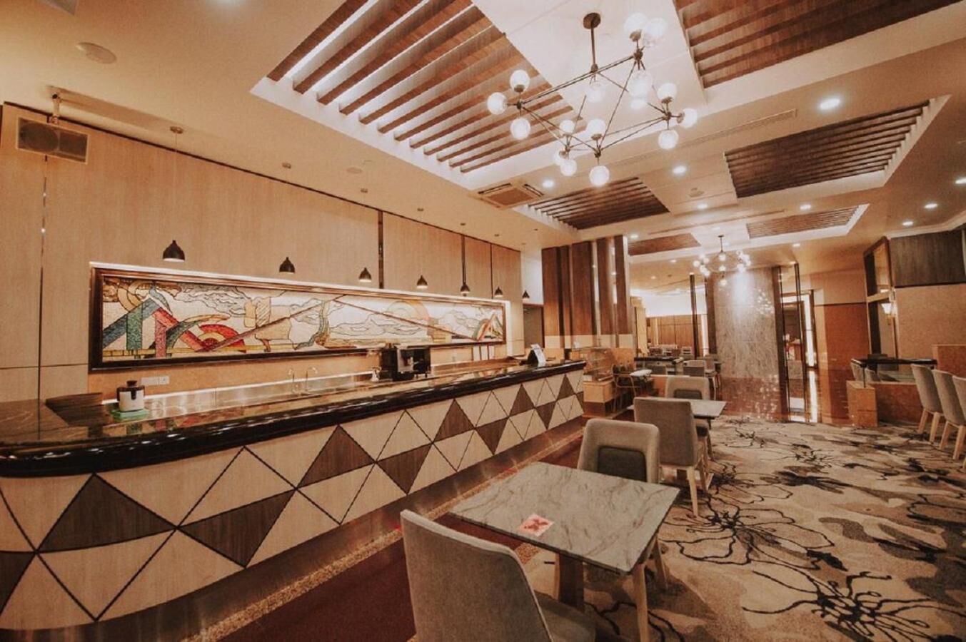 A hotel lobby with a reception desk, seating area, and a large abstract painting on the wall.