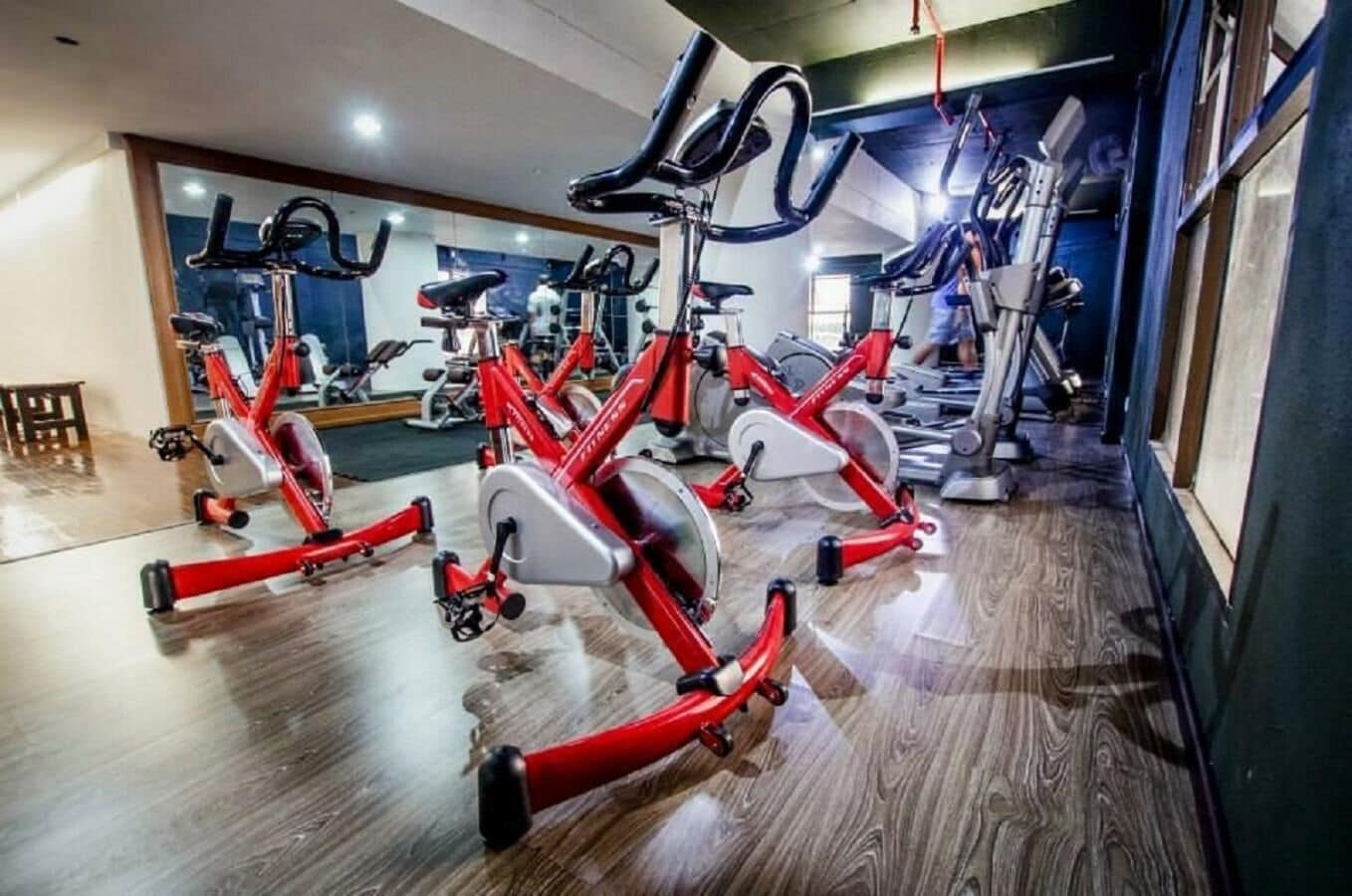Et fitnesscenter med flere røde motionscykler og træningsudstyr.