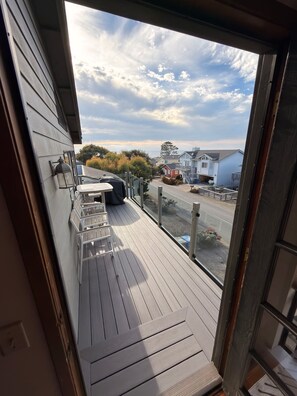 A balcony with a view of a residential area, a covered table, and a chair.