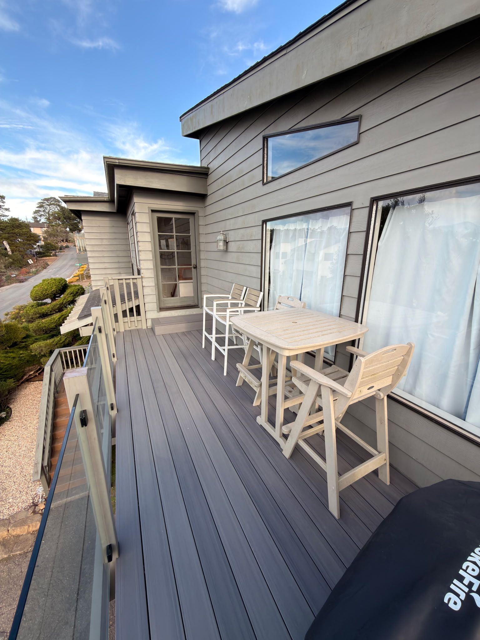 Une terrasse avec une table et des chaises, une porte-fenêtre coulissante et une vue sur la rue.