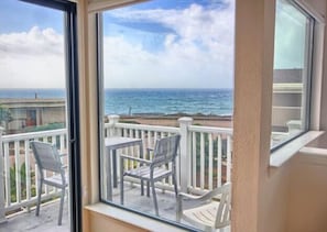 Enjoy the ocean view from this balcony with two chairs and a table.
