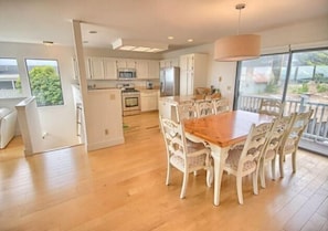 Enjoy meals together at the central dining table, surrounded by large windows offering views of the outdoors.