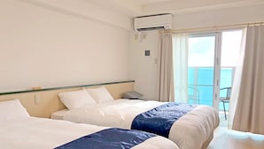 Quarto de hotel com duas camas, varanda e vista, e ar condicionado.