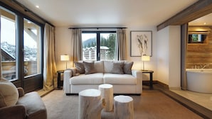 A modern living room with a white sofa, two side tables, and three wooden stools. - The Lodge Verbier (Bagnes)