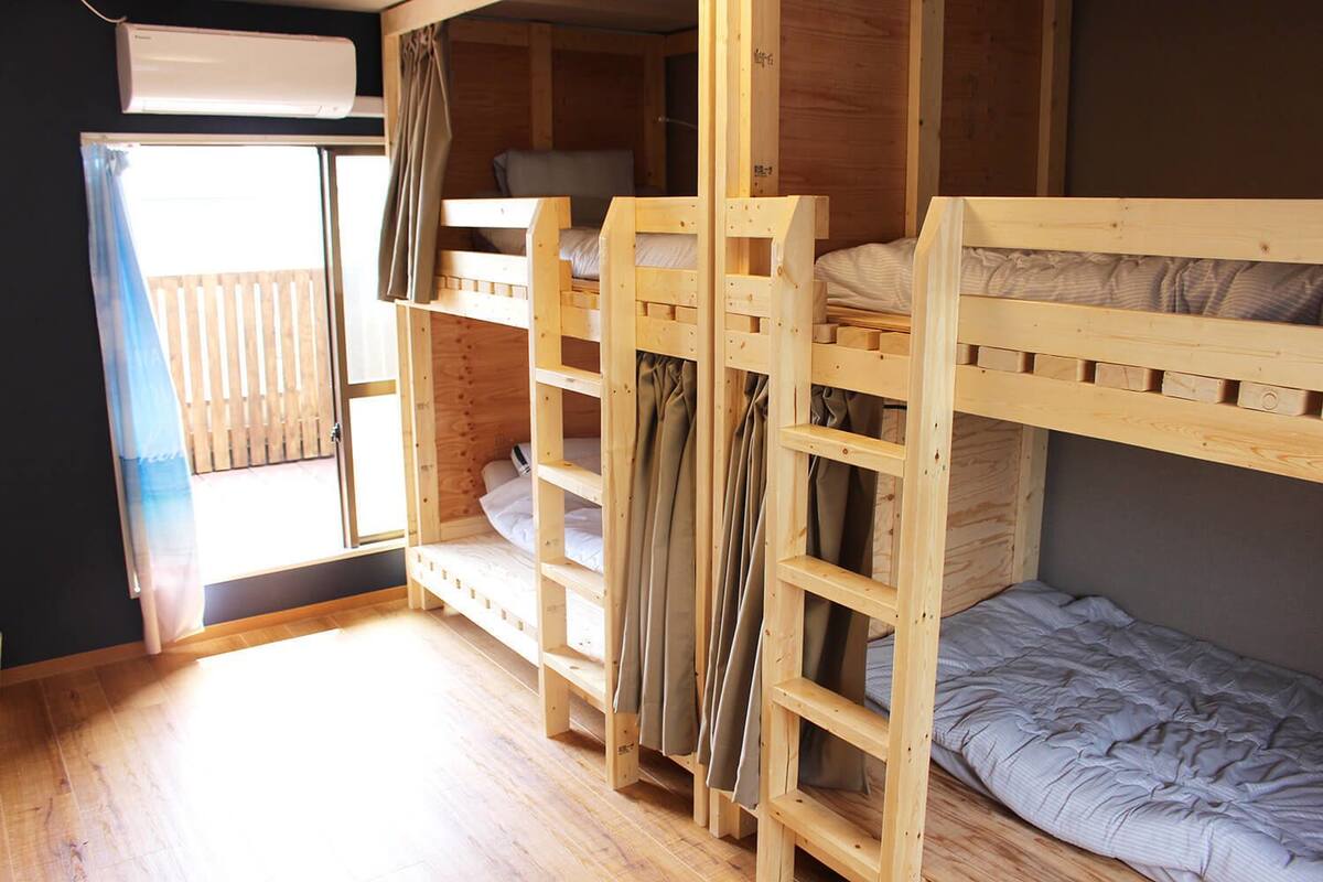 Una habitación con dos literas, una ventana con cortinas y piso de madera.