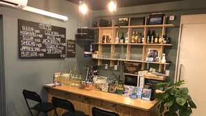 A bar area with a menu board, shelves with bottles, and bar stools.