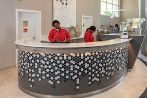 A reception desk with a modern design, a large vase, and a sign indicating breakfast service.