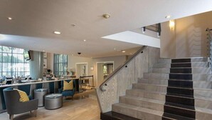 Un interior moderno con una escalera, una zona de estar y un bar.