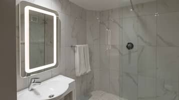 Un baño moderno con un espejo grande, un lavamanos y una ducha.