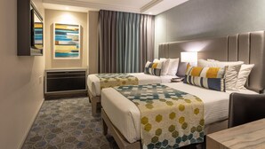 A hotel room with two beds, a desk, a chair, a bathroom, and a large window with curtains. - StayEasy Mbombela (Mbombela)