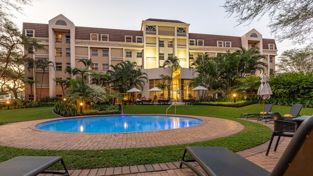 Un hotel con piscina, sillas de descanso y un jardín bien cuidado.