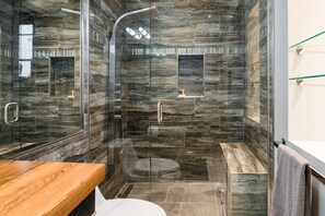 A modern bathroom with a glass-enclosed shower, a wooden vanity, and a white toilet. - Heated Pool, Hot Tubs, & Style Near French Qtr – Great for Families & Groups (New Orleans)