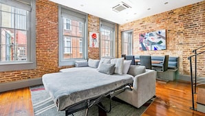 A modern room with a large bed, a sofa, and a dining area. - Heated Pool, Hot Tubs, & Style Near French Qtr – Great for Families & Groups (New Orleans)