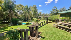 A well-maintained garden with a wooden fence, picnic tables, and a pool area. - Bridge Motel Wellington (Wellington)