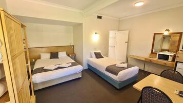 Une chambre d’hôtel avec deux lits, un bureau, un four à micro-ondes et un miroir.