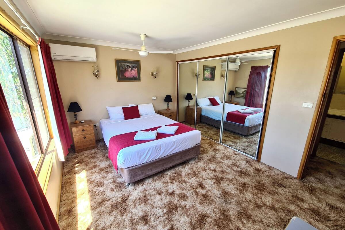 A bedroom with a large bed, a mirror, and a window with curtains.