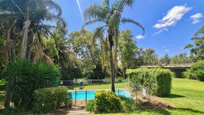 A lush garden with a swimming pool, surrounded by various trees and a bridge in the background. - Bridge Motel Wellington (Wellington)