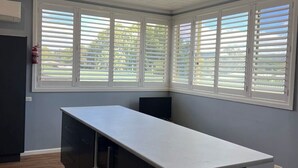 A modern kitchen with a large island, white window blinds, and a grid ceiling. - Bridge Motel Wellington (Wellington)