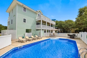 A two-story house with a swimming pool, a covered porch, and a fenced backyard.