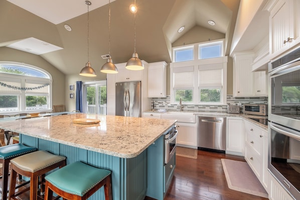 A spacious kitchen with a large island, stainless steel appliances, and a view to the outdoors.