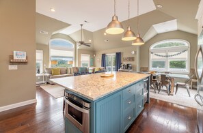 A spacious kitchen with a large island, modern appliances, and a high ceiling with pendant lighting.