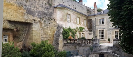 A courtyard with a stone wall, a staircase, and a building with multiple windows.